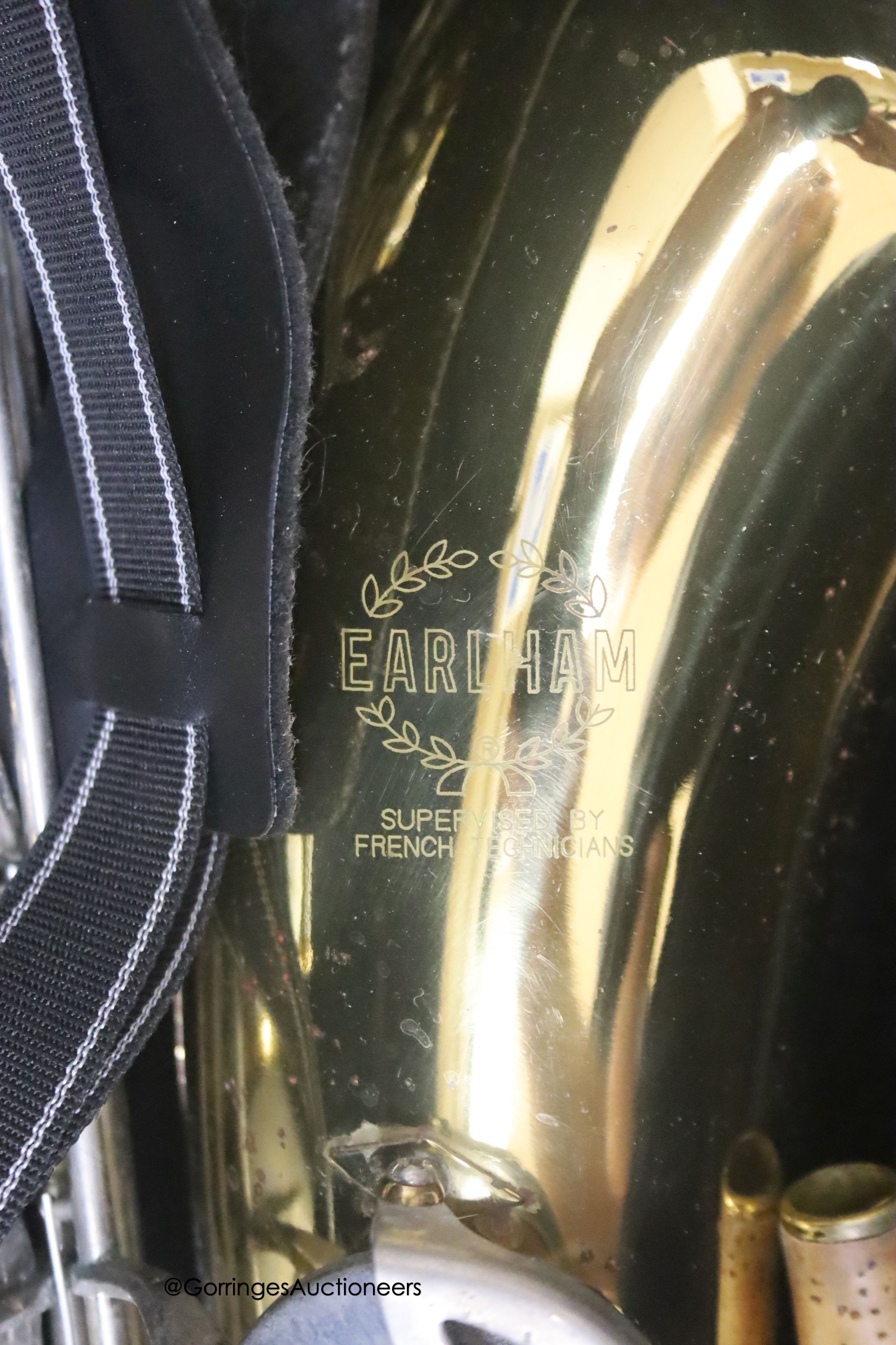 A cased Earlham brass saxophone and music sheets